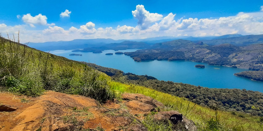 An idyllic hill station in Kerala with serene views of a tranquil lake, surrounded by rocky terrains