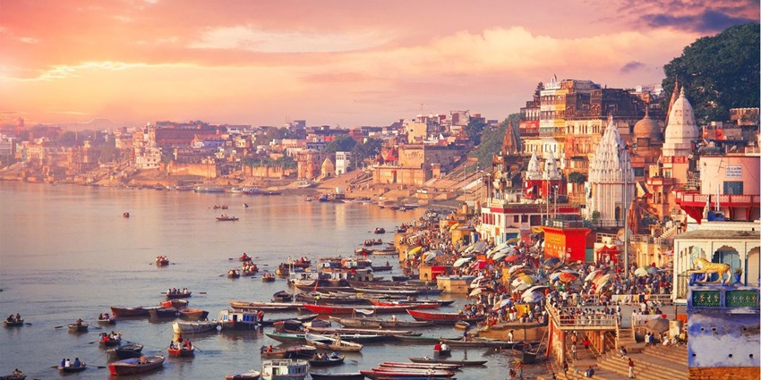 A serene riverside view of the Varanasi Ganga ghats casting sunset hue over the old temples.