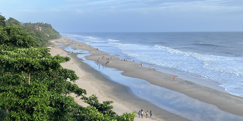 A breathtaking view of people enjoying at Varkala Beach with a backdrop of blue sky