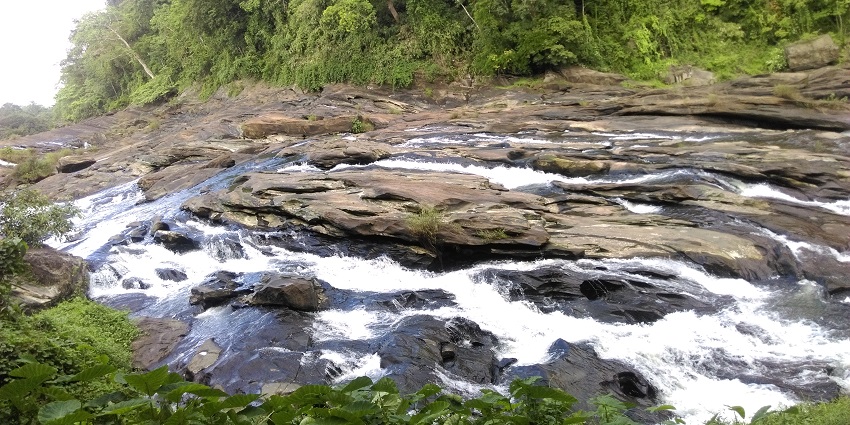Sit by the rocky shores of Vazhachal Falls with your partners and sink in nature’s embrace