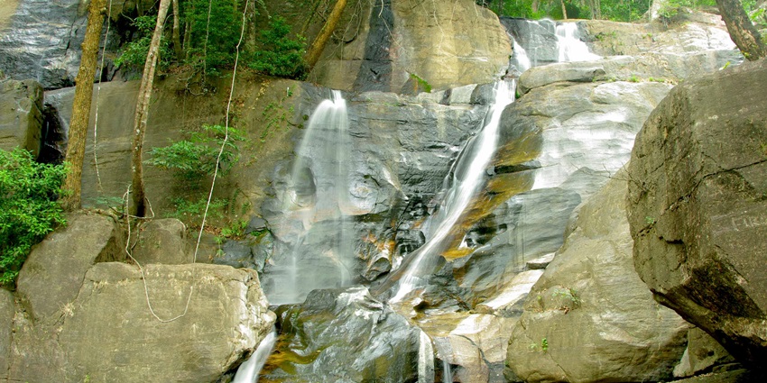 A picture of a rocky mountain with a small waterfall cascading down into a pond