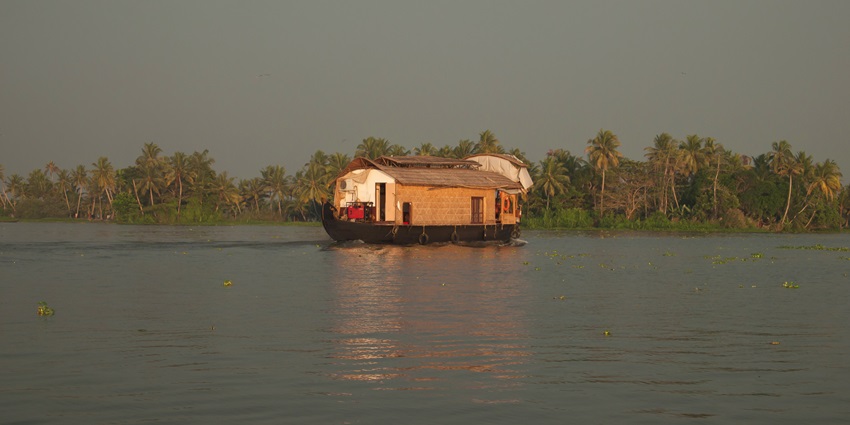 A mesmerising view of the Vembanad Lake near Kumarakom with a houseboat floating on it.
