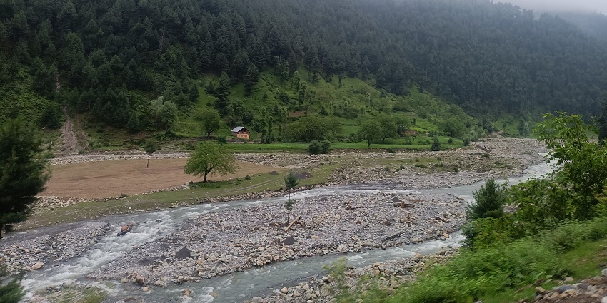 Scenic view of forested hills, meadows, and houses in Kapran Valley, Verinag, Anantnag
