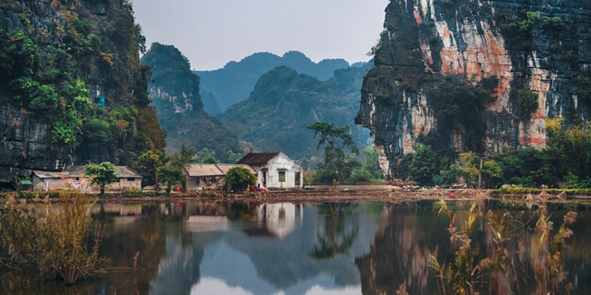 A mesmerising view of two houses located between rocky mountains & lush greenery