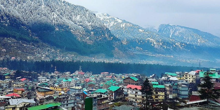 Aerial view of the city of Manali looking over the snow covered himalayan range beyond