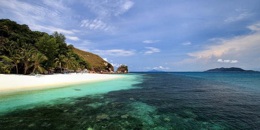 View of Rawa Island showcasing crystal-clear waters, white sandy beaches, and lush greenery.