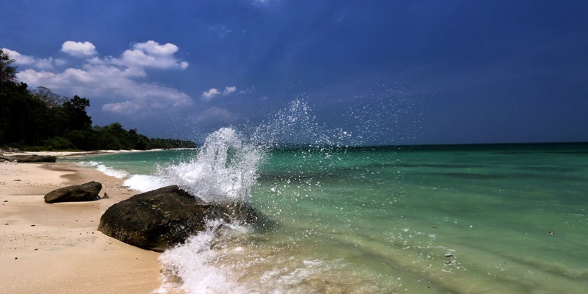A stunning view of a beach with a rush of waves approaching the golden shore