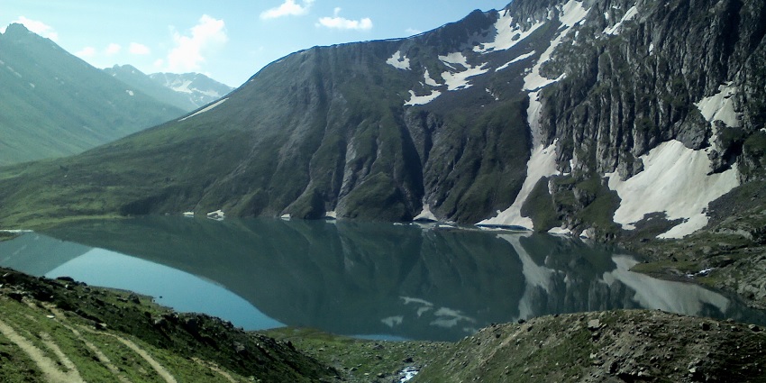 Vishansar Lake, with turquoise waters, is nestled amongst half-snow-covered mountains
