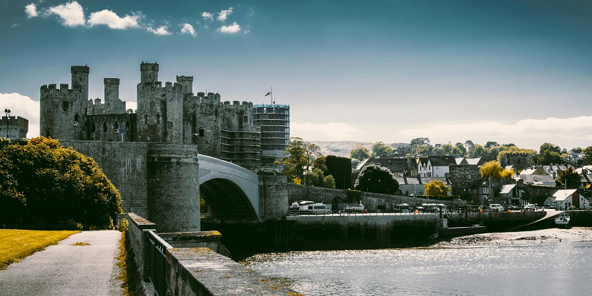 View of an ancient castle with a river body flowing on the side in Wales in Britain