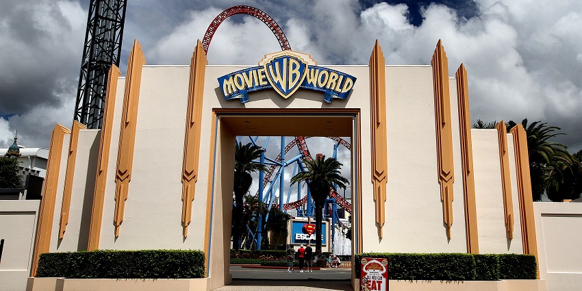 Entrance to Warner Bros. Movie World theme park with roller coasters and cloudy sky