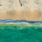 A breathtaking view of a body of turquoise waters with a blue parachute on the ground.