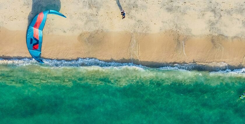 A breathtaking view of a body of turquoise waters with a blue parachute on the ground.