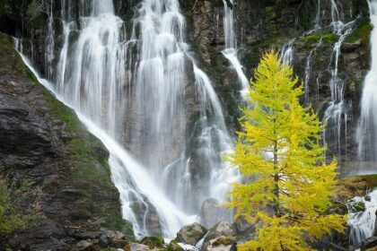 A stunning view of a waterfall flowing freely surrounded by lush greenery during the day.