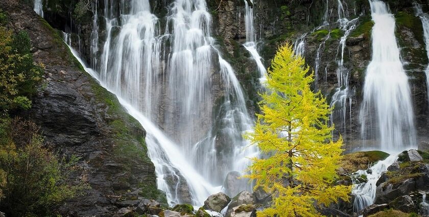 A stunning view of a waterfall flowing freely surrounded by lush greenery during the day.