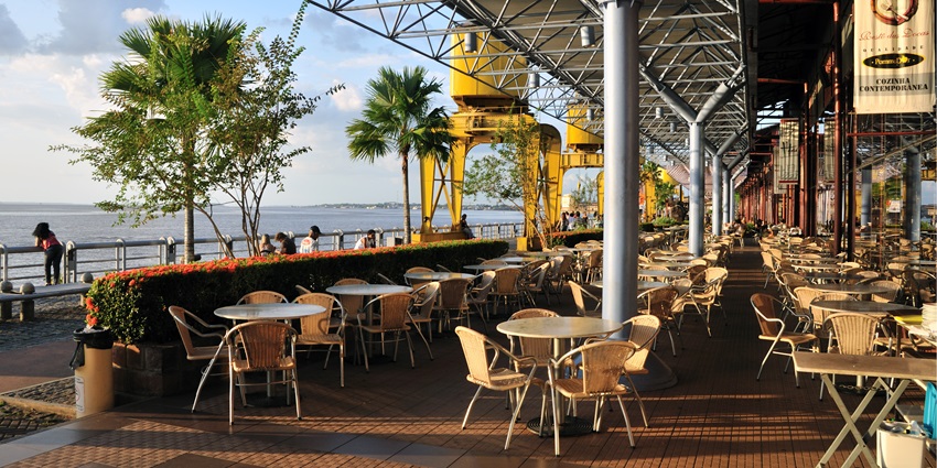 A beautiful restaurant with rustic decor and a view of the sea on one side.