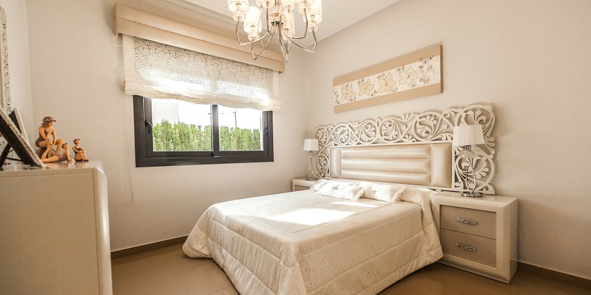 A view of a bedroom with a bed lined with white sheets and lamps on the side table.