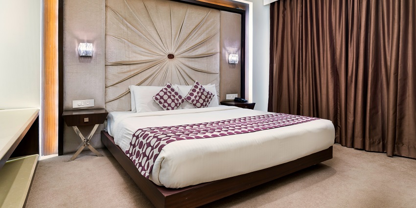 A stunning view of a beautiful room in a hotel with a bed and brown curtains on the side.
