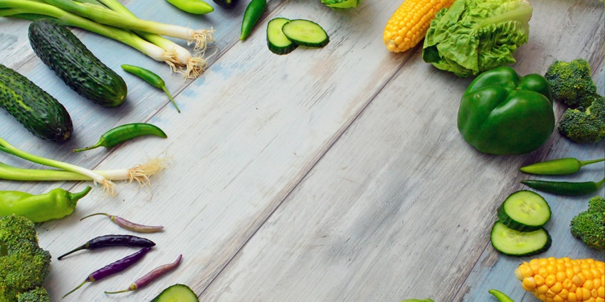 A view of assorted vegetables including zucchini and lettuce on a brown wooden table.