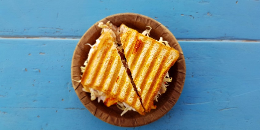 A view of a brown plate with a gilled sandwich with vegetables in it served on a table.