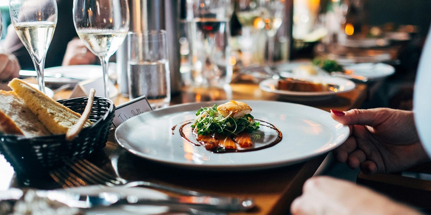 A mouth-watering view of a meal on a ceramic white plate kept on a table in a restaurant.