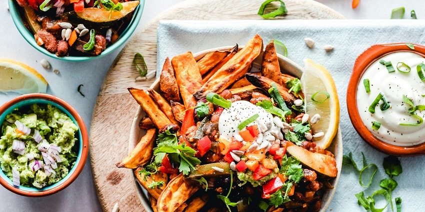 A top view of a plate with fries served on it with a side of different dips and salsa.