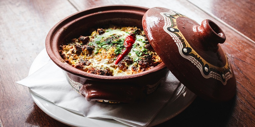 A view of a brown kept on a table served with a meal garnished with red chillies.