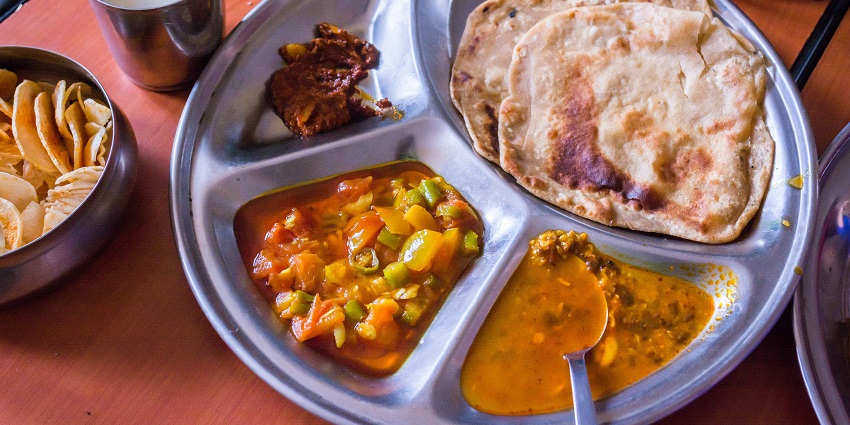 A picture of delicious North Indian food that is served on a round plate at a restaurant