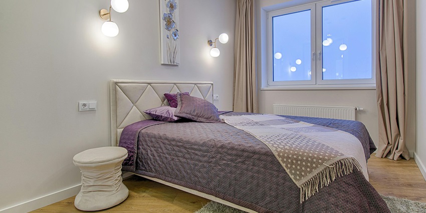 A view of a bedroom with a bed lined with dark-coloured sheets and open curtains.