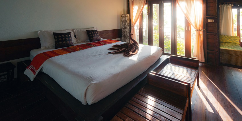 A view of a hotel room with open curtains and a bed with white sheets and pillows on it.