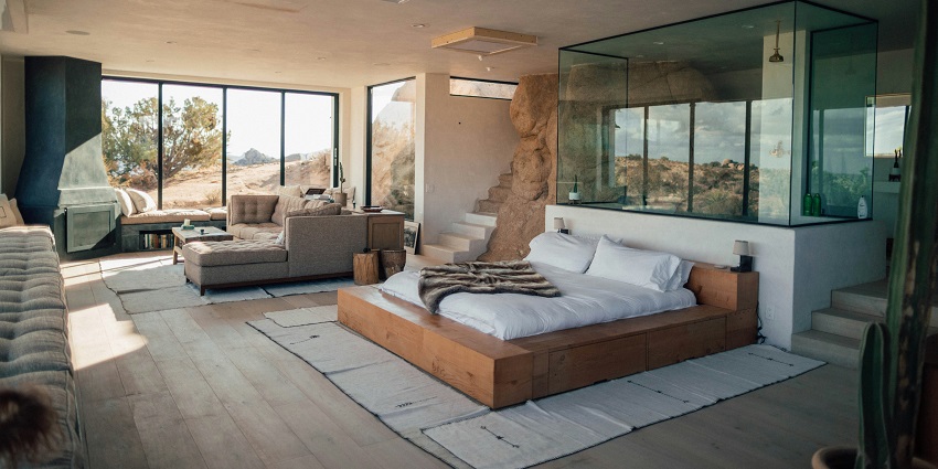 A view of a bedroom with a brown bed and white sheets and a sofa set on the side.