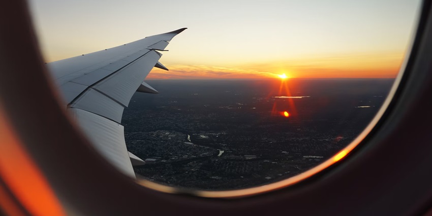 The window view of an aeroplane capturing a beautiful sunset above the buildings.