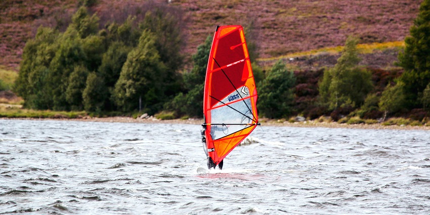 A view of a person with an orange surfing board in the middle of a body of water.