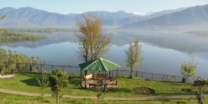 The calm Wular Lake surrounded by mountains and green valleys in Jammy and Kashmir.