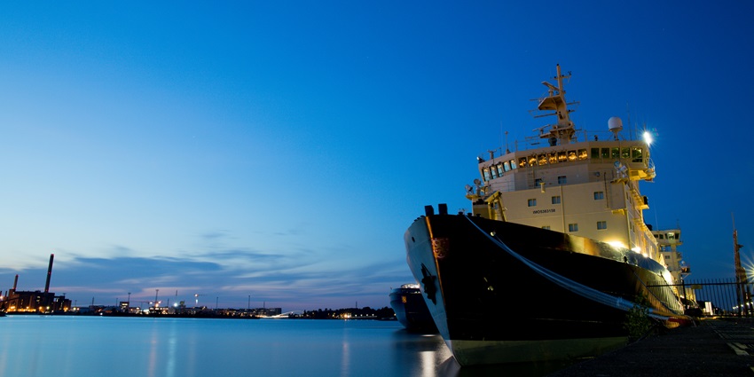 A black and white ship docked at the port in the evening.