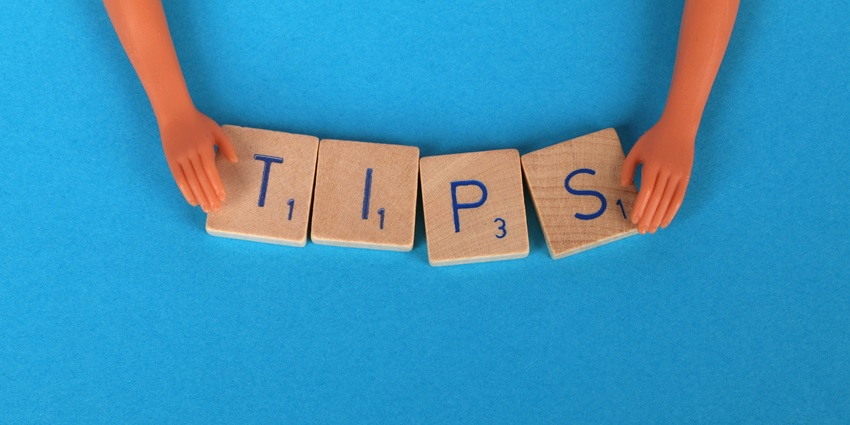 A unique view of Scrabble tiles saying tips individually placed on a dark blue background.