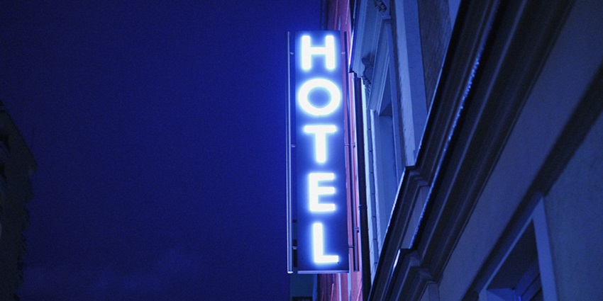 where to stay ALT text: A view of a building with a signboard saying hotel in bold letters in a red light.