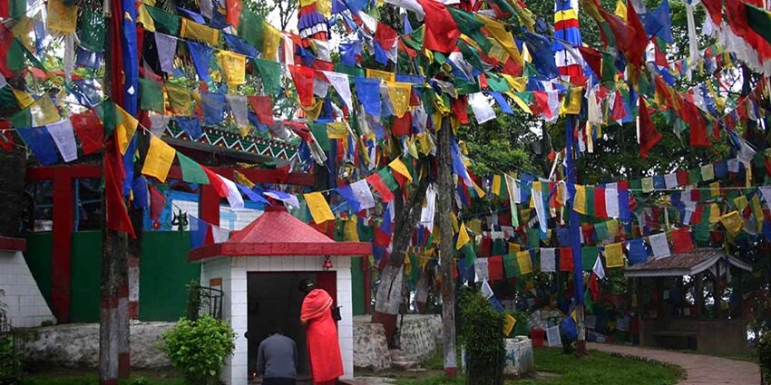 A lot of multicolour flags put up in front of a temple