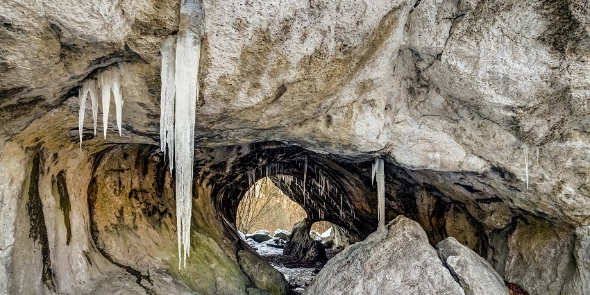 A dark cave entrance surrounded by rocky terrain, hinting at hidden wonders inside.