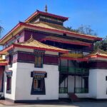 A breathtaking view of a monastery in Sikkim with red and yellow walls during the day.