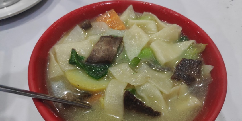 Image of a Thenthuk in a red bowl, mixed vegetables and meat - best food in Gangtok