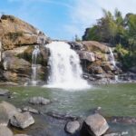 Lush greenery surrounds the cascading Neer Veezhcha Waterfalls in a serene natural setting