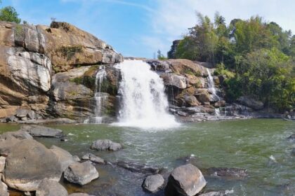 Lush greenery surrounds the cascading Neer Veezhcha Waterfalls in a serene natural setting