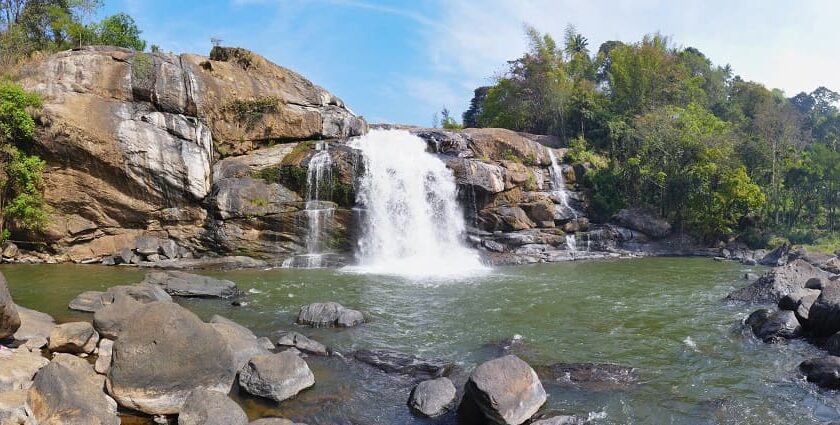 Lush greenery surrounds the cascading Neer Veezhcha Waterfalls in a serene natural setting