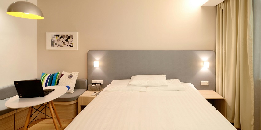 A hotel room surrounded by a cosy workspace with a plant and notebook.