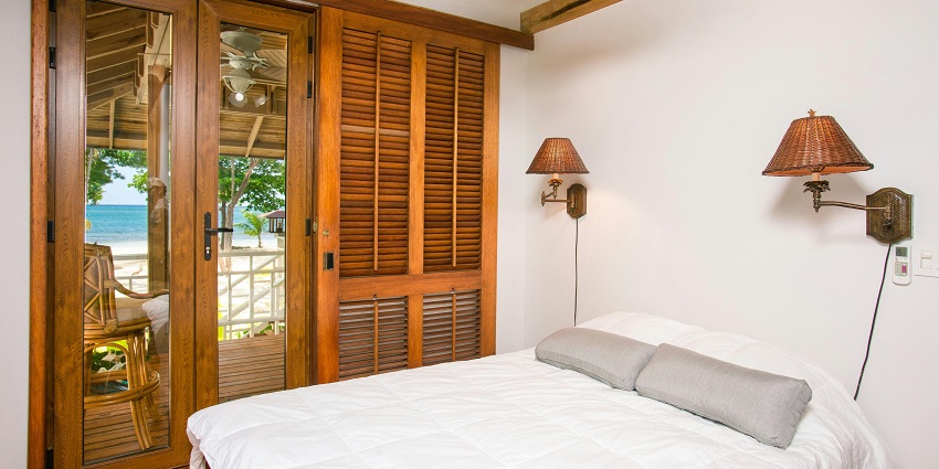 Image of a hotel room, closed wardrobe and bed near the glass door and scenic view outside.