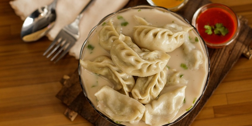 Steamed dumplings filled with savory ingredients, served with dipping sauce.