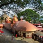 An aerial view of a temple in Assam with red and white architecture during the daytime.