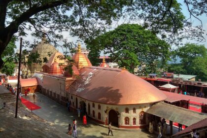 An aerial view of a temple in Assam with red and white architecture during the daytime.