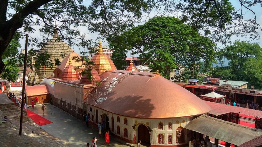 An aerial view of a temple in Assam with red and white architecture during the daytime.