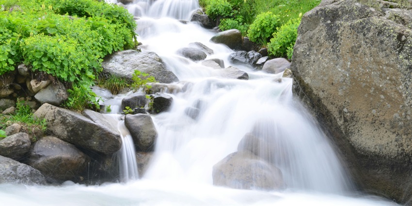 Enchanting view of a waterfall flowing through rocks during the daytime around greenery.